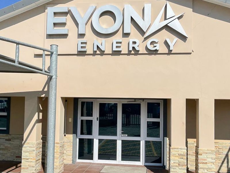 Front facade of a commercial building featuring prominent signage, stone cladding accents, and a glass entrance door.