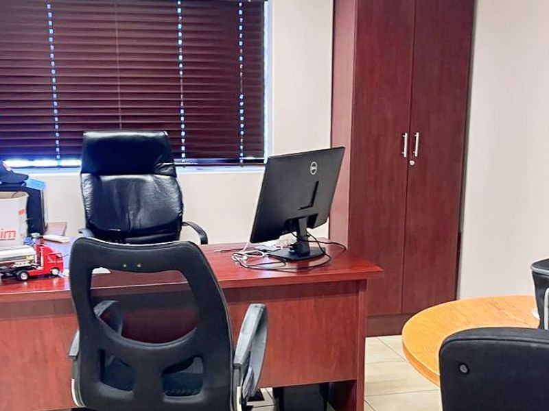 A functional office space featuring tiled flooring, a built-in storage cupboard, and venetian blinds for light control.
