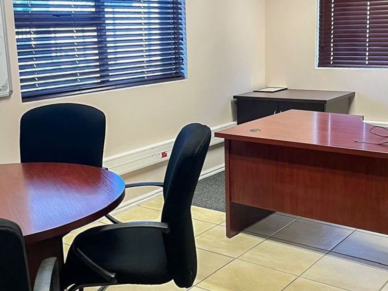 A functional commercial office space featuring tiled flooring, venetian blinds, and surface-mounted electrical trunking for connectivity.
