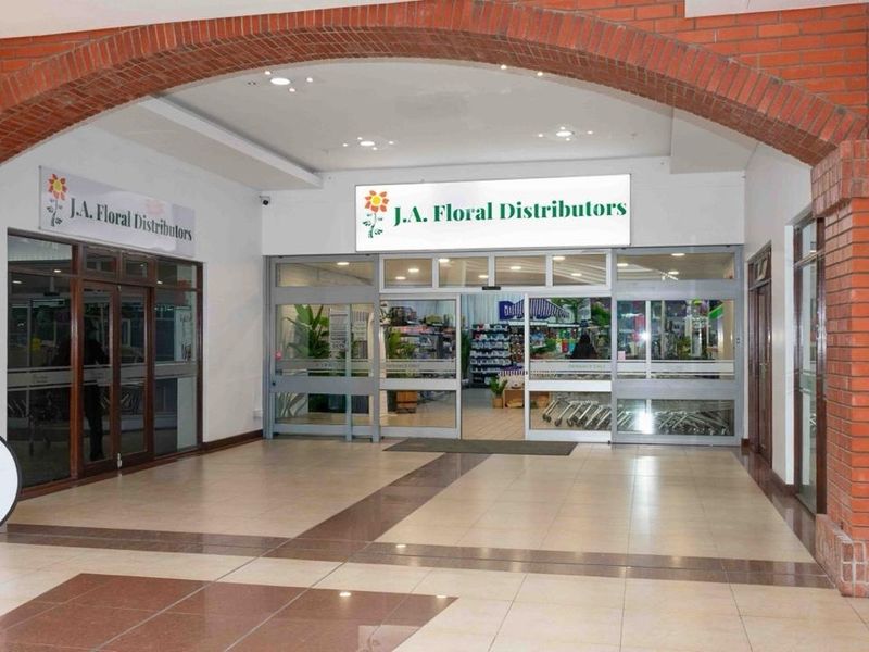 Commercial entrance area featuring a decorative brick archway, tiled flooring, and glass storefront access to the floral distribution unit.