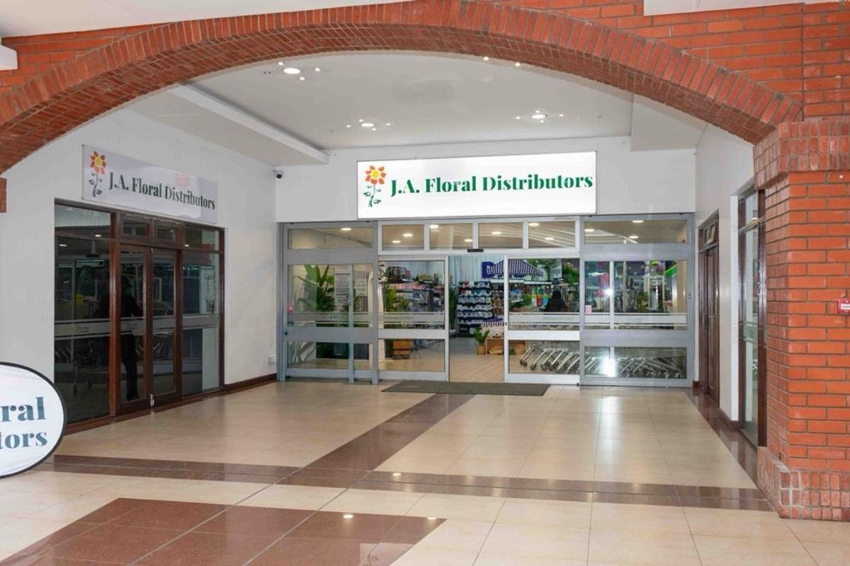 A clean and well-maintained retail entrance featuring a decorative brick archway, tiled flooring, and clear glass storefront access.