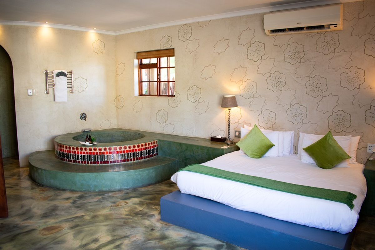 Spacious bedroom featuring a unique integrated circular bathtub, decorative wall finishes, tiled flooring, and a wall-mounted air conditioning unit.