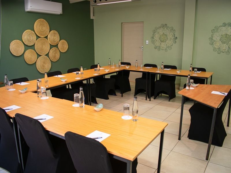 A functional meeting or conference room featuring tiled flooring, a wall-mounted air conditioning unit, and neutral green wall finishes.