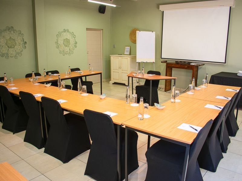 A functional conference or meeting room equipped with a projector screen, tiled flooring, and ample space for professional gatherings.