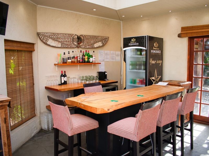 A well-appointed indoor bar area featuring a natural wood countertop, recessed lighting, and direct access to the outdoor space through glass doors.