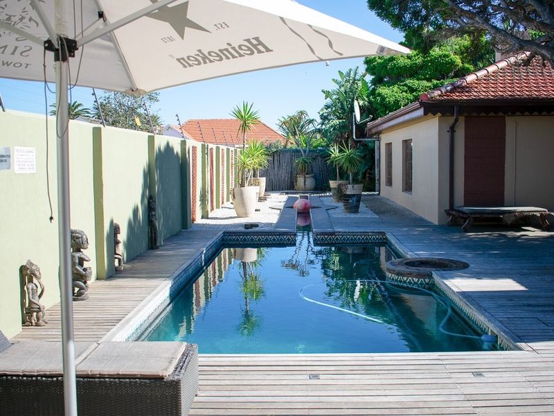 Outdoor pool area featuring timber decking, a rectangular swimming pool, and a perimeter wall with electric fencing.