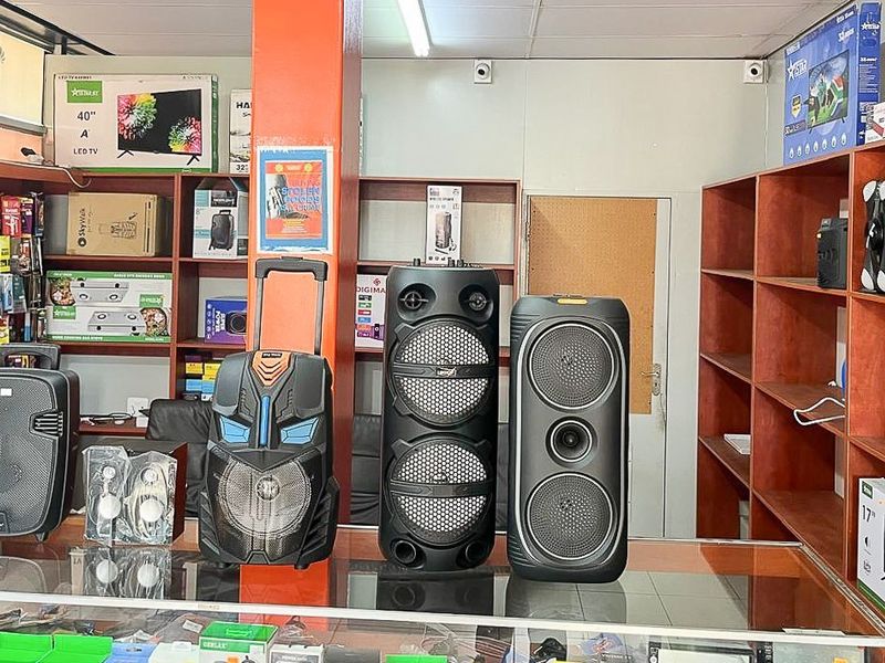 Retail shop interior featuring extensive built-in wooden shelving units and a glass display counter for product presentation.