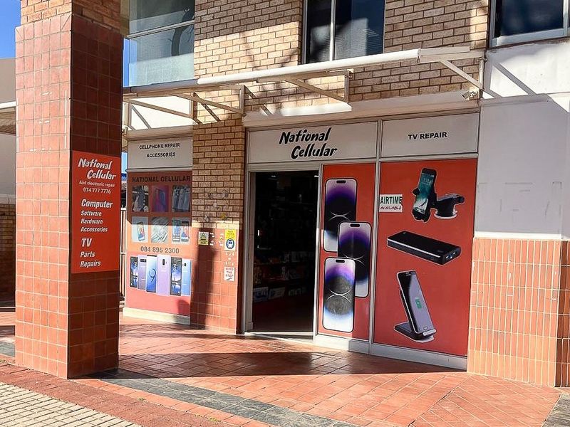 Front facade of a retail storefront featuring brick construction, a tiled entrance area, and large glass display windows with signage.