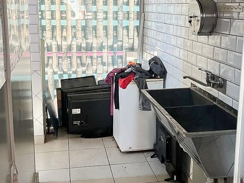 Utility scullery area featuring a double stainless steel sink, subway tile backsplash, and tiled flooring, suitable for commercial prep or wash-up tasks.