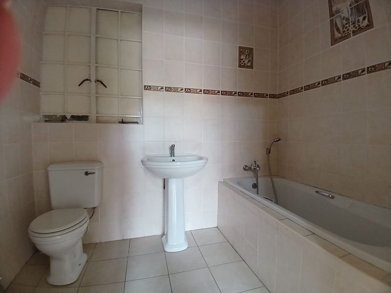 A functional bathroom featuring a pedestal basin, toilet, and bathtub with tiled finishes throughout.