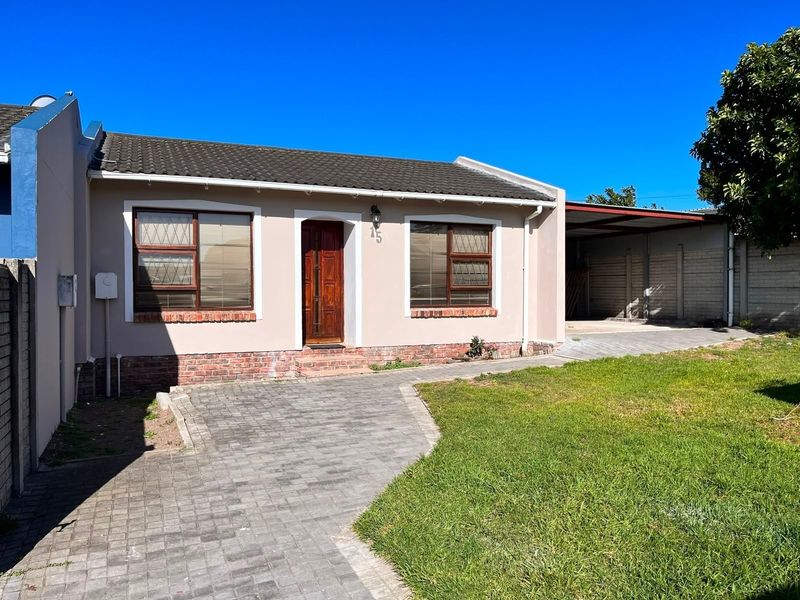 Front elevation of a single-story house featuring a paved driveway, attached carport, and well-maintained garden area.