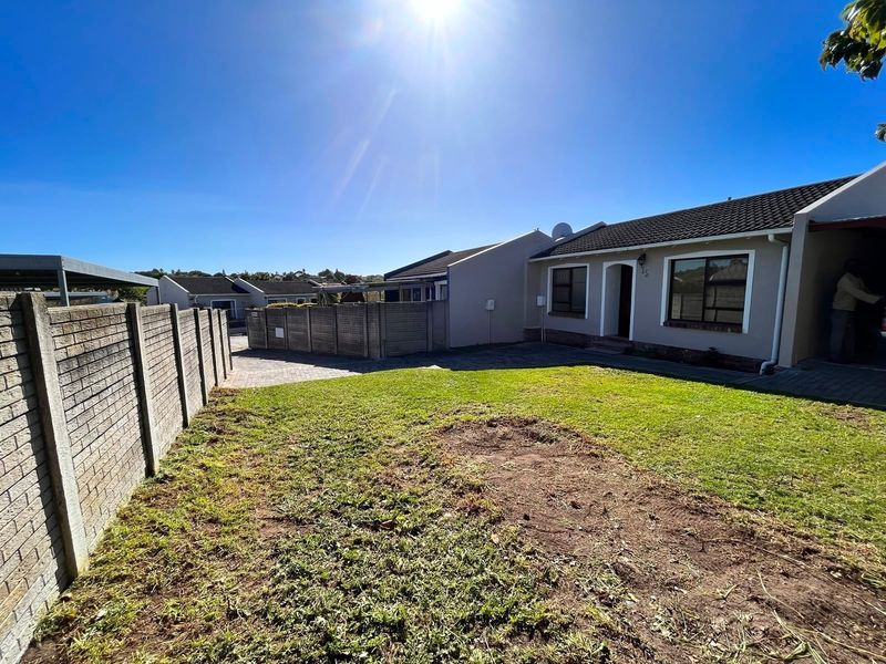 Front view of the property featuring a paved driveway, precast boundary wall, and a lawn area leading to the main entrance.
