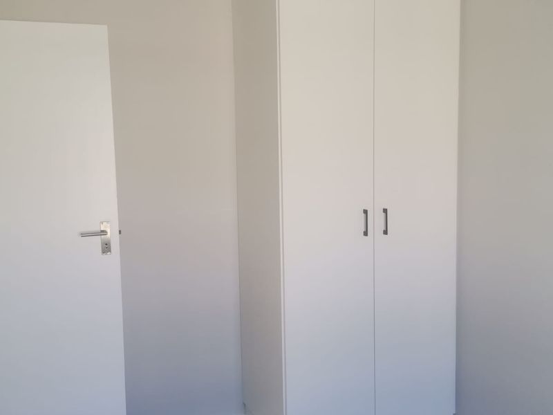 A clean, neutral bedroom featuring modern built-in wardrobes, tiled flooring, and coved ceiling details, presenting a well-maintained and ready-to-occupy space.