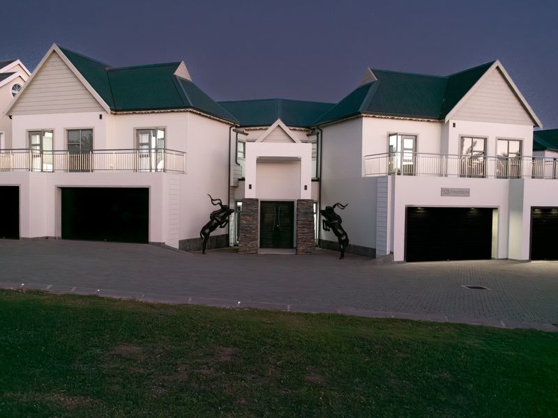 A modern double-story residence featuring a symmetrical facade, dual garages, upper-level balconies, and a paved driveway with stone-clad entrance details.