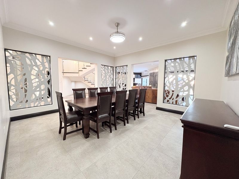 Spacious dining room featuring modern tiled flooring, recessed downlights, and unique decorative laser-cut metal room dividers providing an open-plan feel.