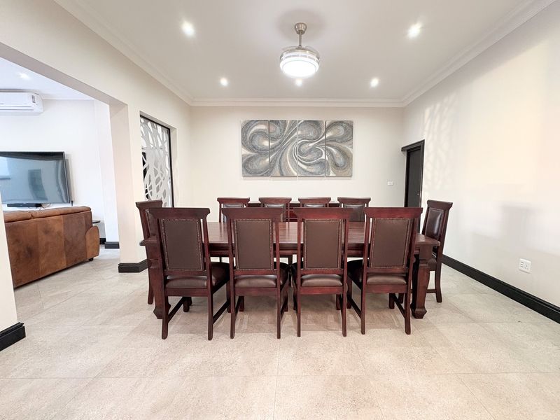 Spacious dining room featuring neutral tiled flooring, recessed downlighting, and a central ceiling fan, creating a bright and well-maintained area for formal dining.