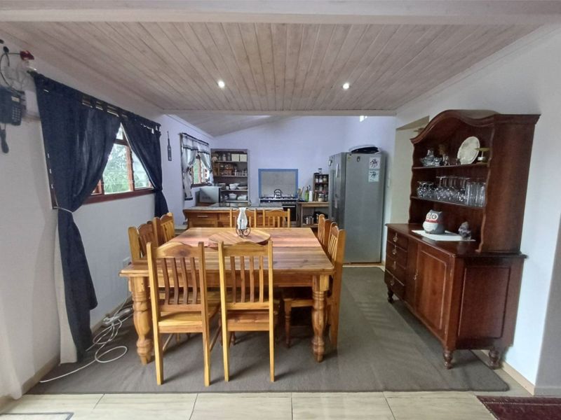 Open-plan living and dining area featuring a timber-clad ceiling, tiled flooring, and a functional kitchen space with built-in cabinetry.