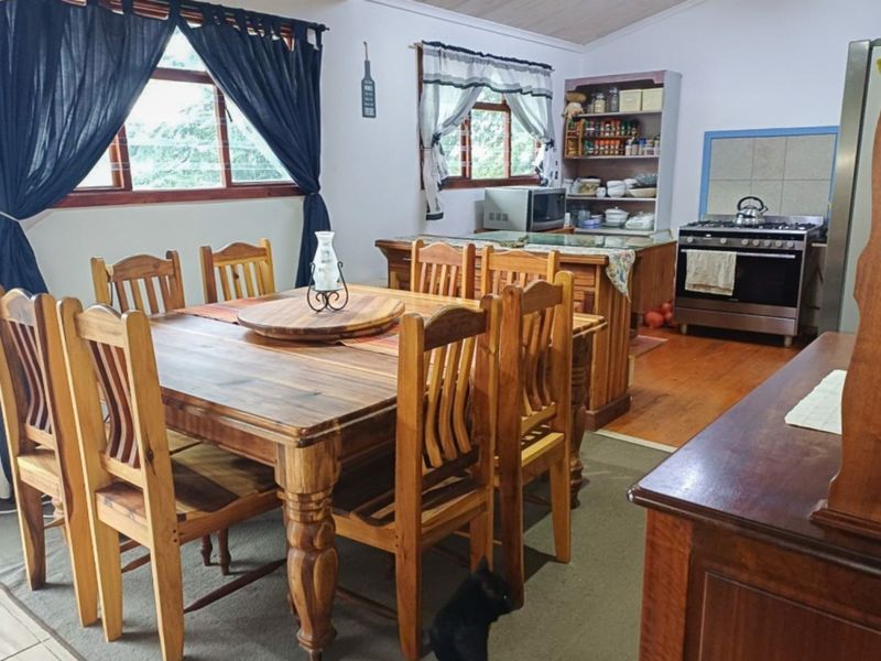 Open-plan kitchen and dining area featuring wooden flooring, timber window frames, and built-in cabinetry with a gas stove.