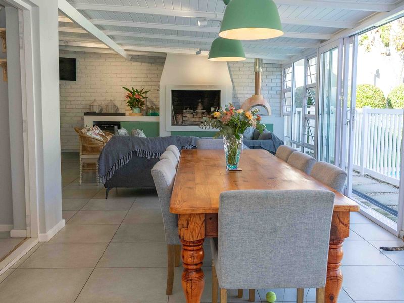 Spacious open-plan living and dining area featuring an exposed brick fireplace, tiled floors, and large sliding doors opening to the outdoor pool area.