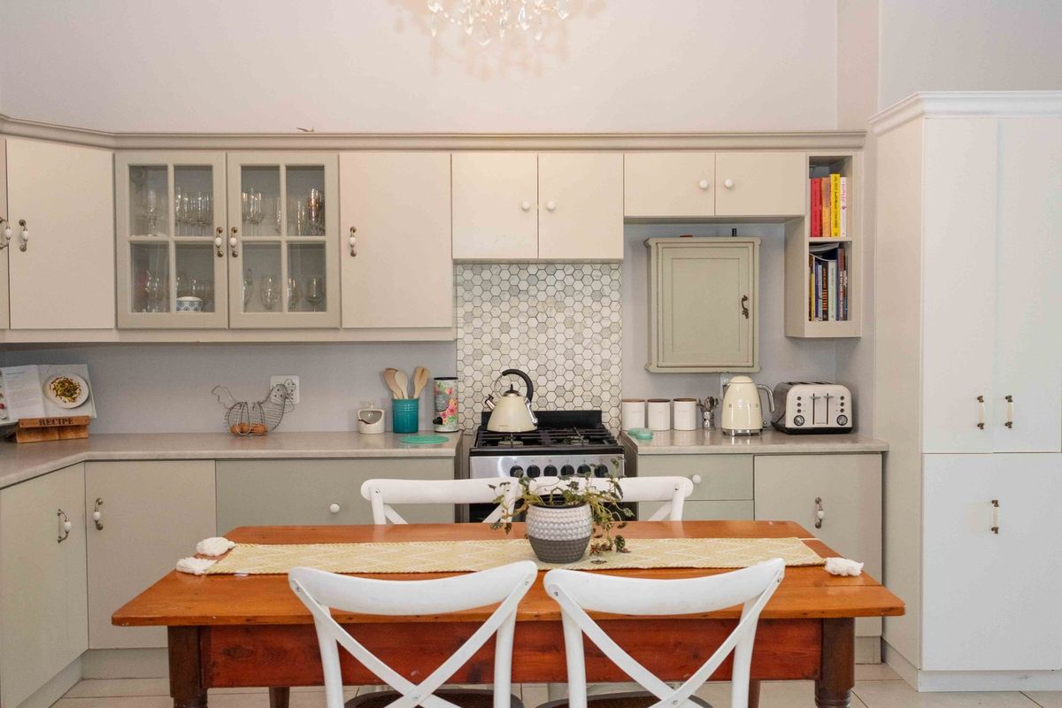 A well-maintained kitchen featuring light-toned cabinetry, a hexagonal tile backsplash, and a freestanding gas stove with integrated storage solutions.