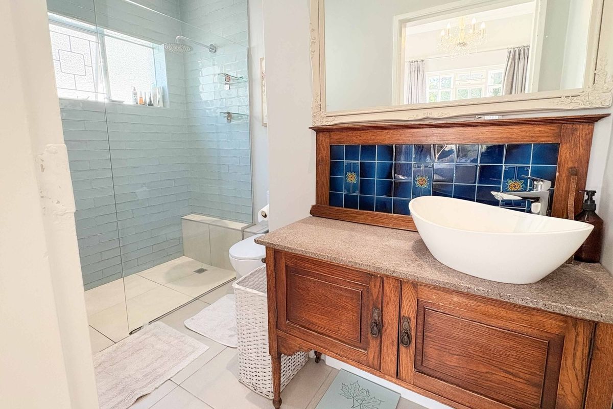 A well-maintained bathroom featuring a walk-in shower with glass enclosure, a stylish vessel sink, and a wooden vanity with decorative tile backsplash.