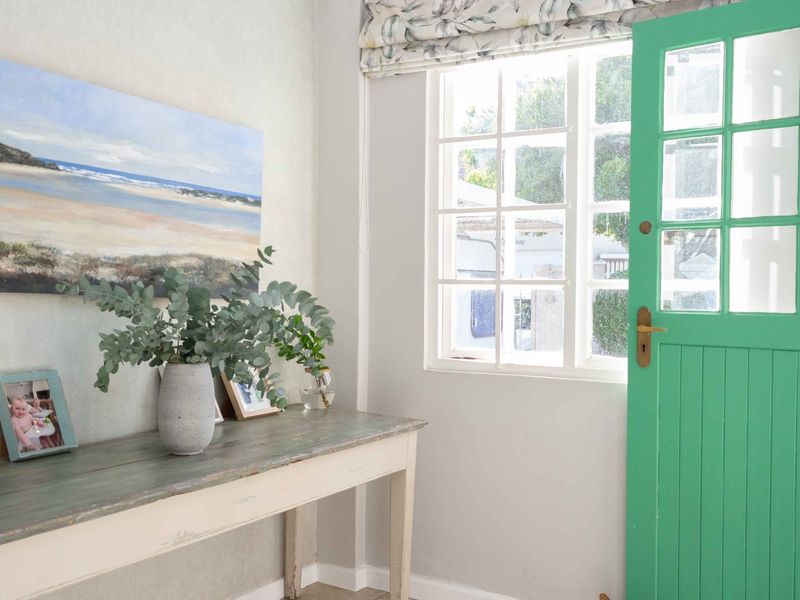 A bright entrance area featuring a distinctive green painted timber door and a classic multi-pane window, creating a welcoming and light-filled transition space.