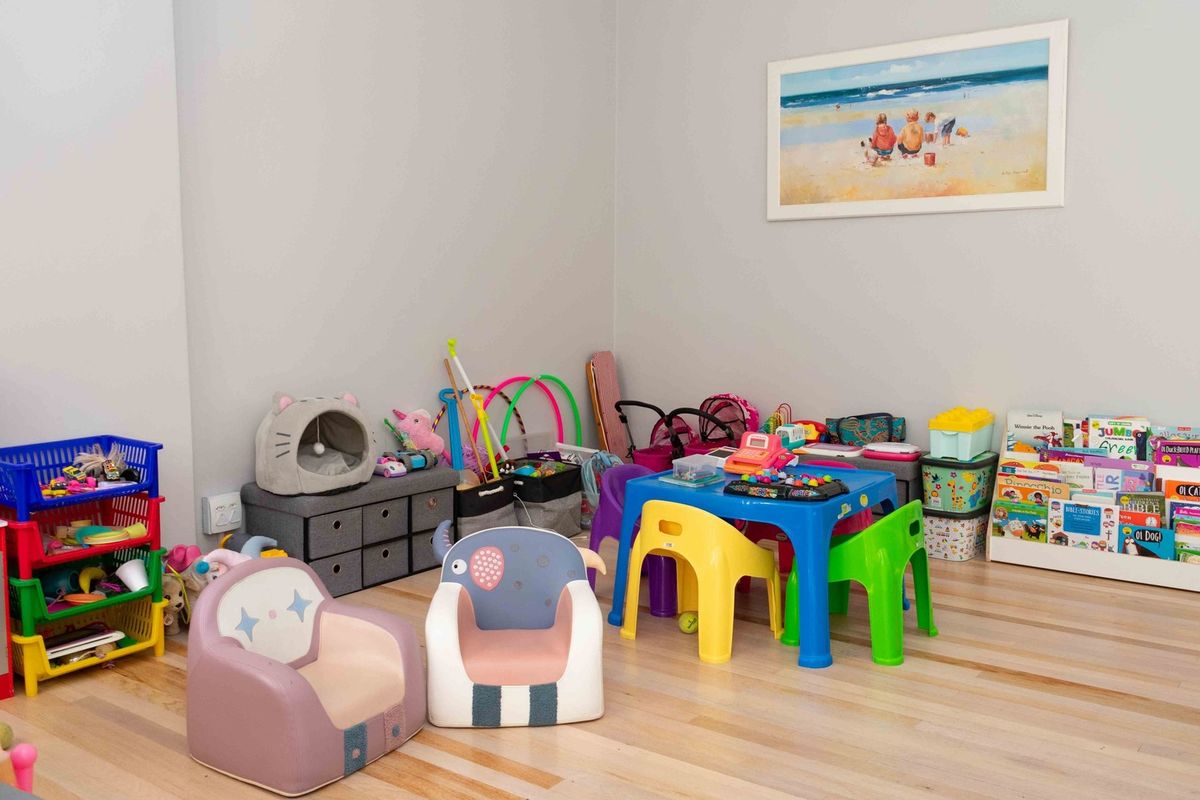 A bright and spacious room currently utilized as a children's play area, featuring light-toned hardwood flooring and neutral wall finishes.