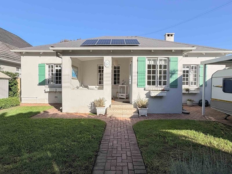 Charming single-story residence featuring a covered front porch, solar panels, and a well-maintained front garden with a brick-paved entrance path.