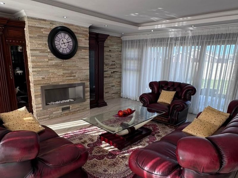 A well-maintained living room featuring a stone-clad fireplace, recessed ceiling lighting, and large sliding glass doors that provide ample natural light.