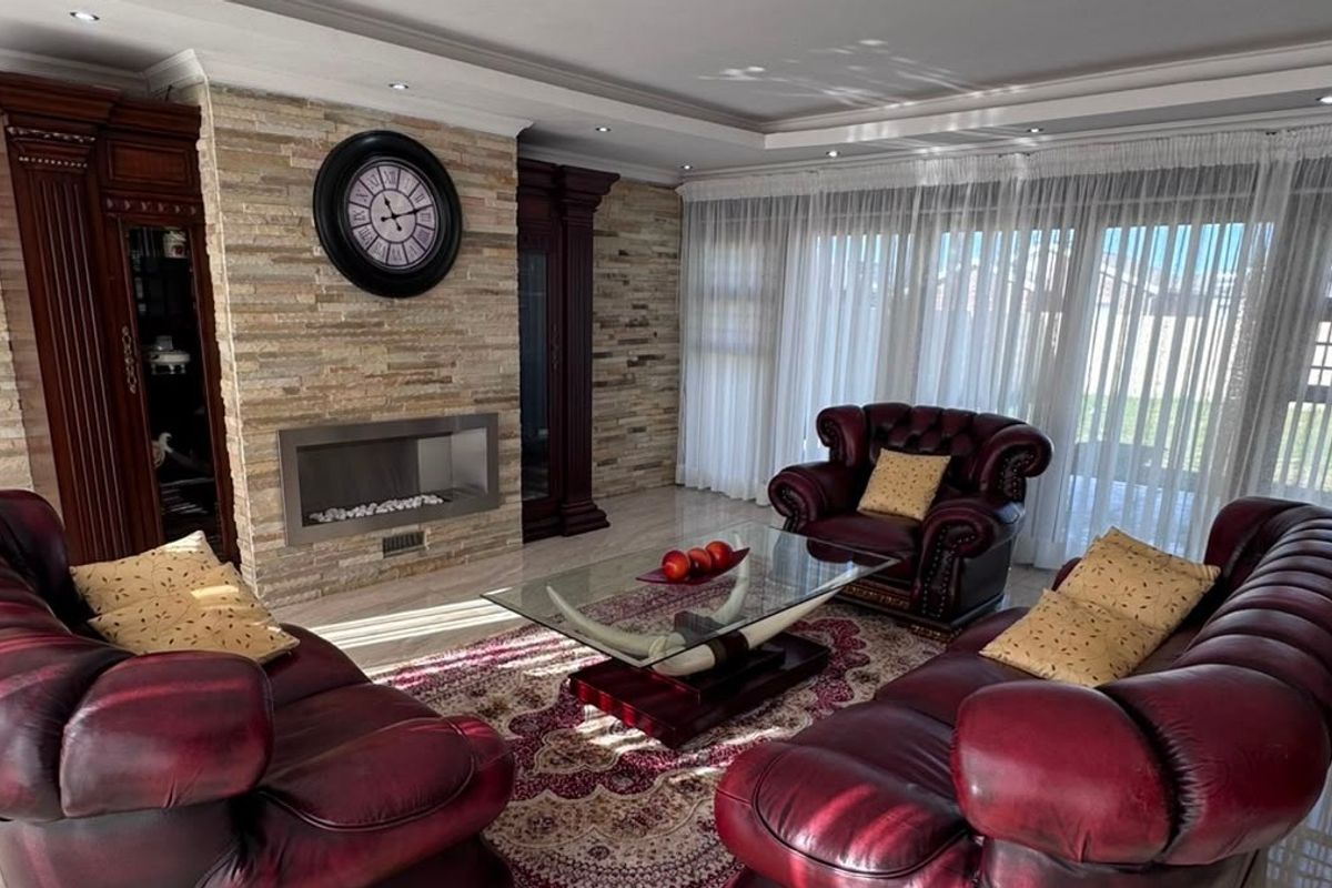 A well-maintained living room featuring a stone-clad fireplace, recessed ceiling lighting, and large sliding glass doors that provide ample natural light.