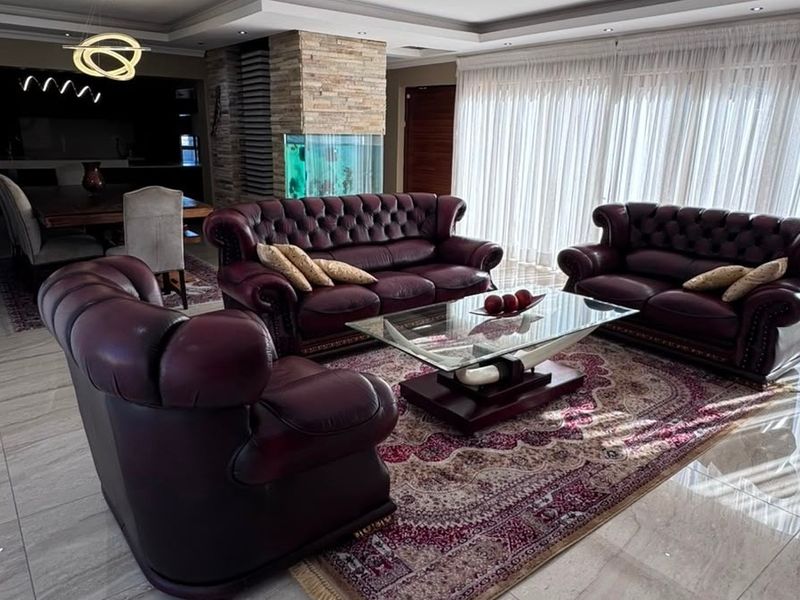 Spacious open-plan living and dining area featuring tiled floors, recessed ceiling lighting, a stone-clad feature pillar, and a built-in aquarium.
