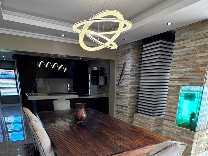 Open plan living and dining area featuring a striking stone-clad feature wall with a built-in aquarium and modern recessed ceiling lighting.