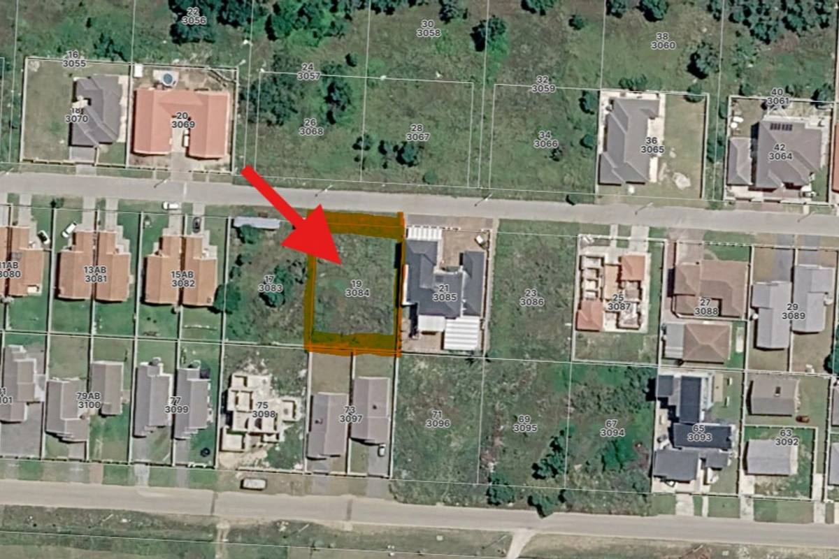Aerial view of a vacant residential land plot in a developed suburban neighborhood, clearly marked for identification.