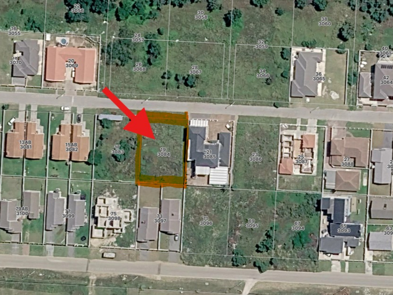 Aerial view of a vacant residential land plot in a developed suburban neighborhood, clearly marked for identification.
