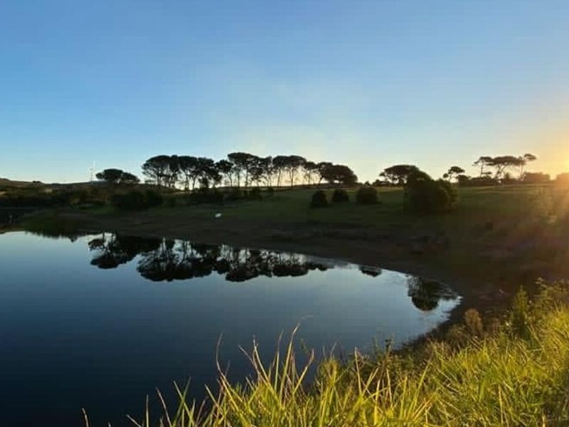 A scenic view of a tranquil lake surrounded by natural landscape at sunset, highlighting the peaceful outdoor environment of the property.