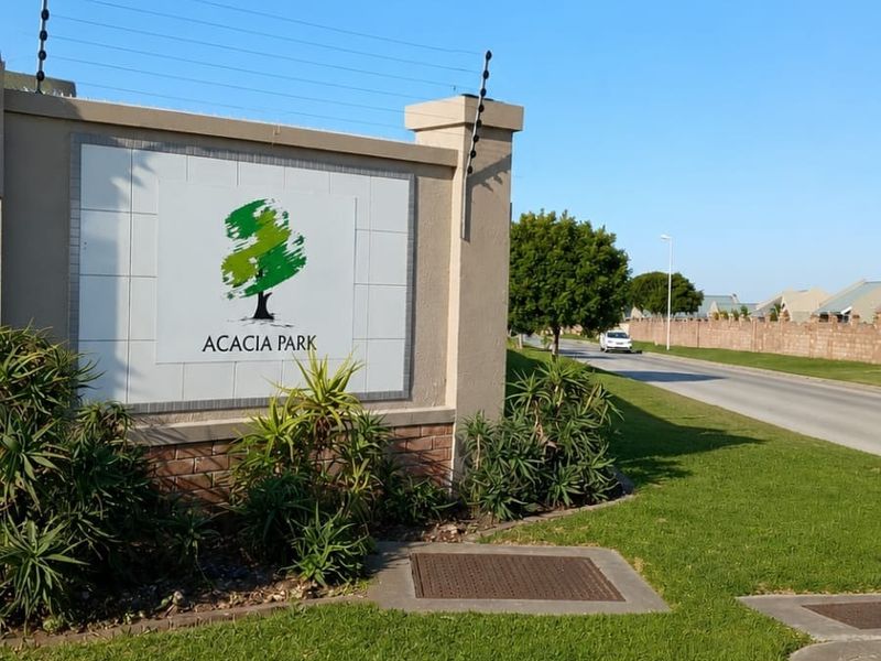 Entrance signage for Acacia Park residential estate featuring a concrete boundary wall with integrated electric fencing and landscaped verge.