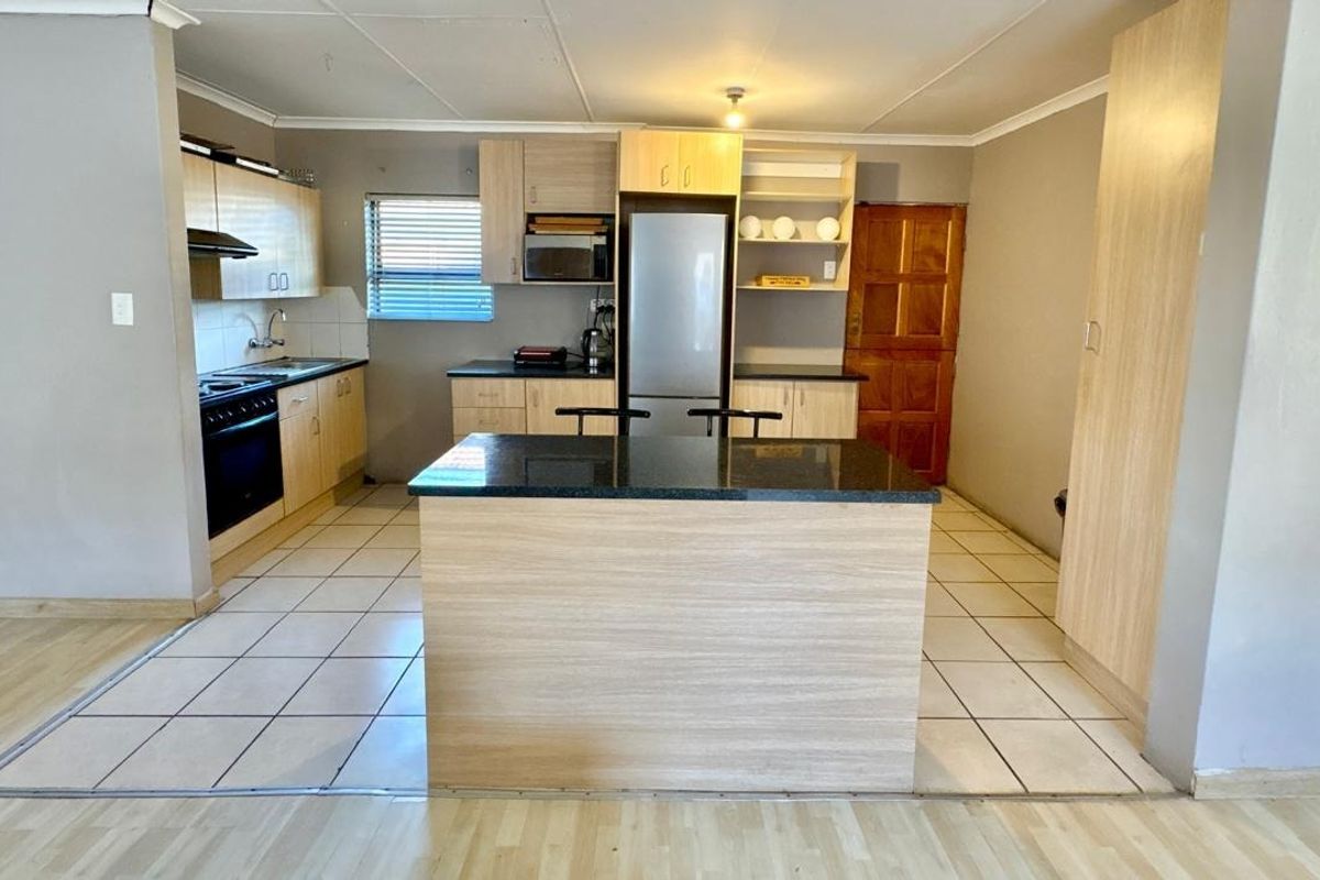 A functional kitchen featuring light wood cabinetry, granite countertops, a central island, and tiled flooring, providing a practical workspace for daily cooking.