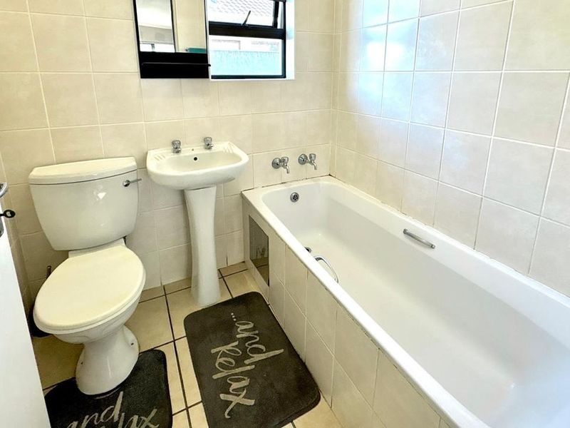 A functional bathroom featuring a pedestal basin, standard toilet, and a bathtub with tiled wall finishes.