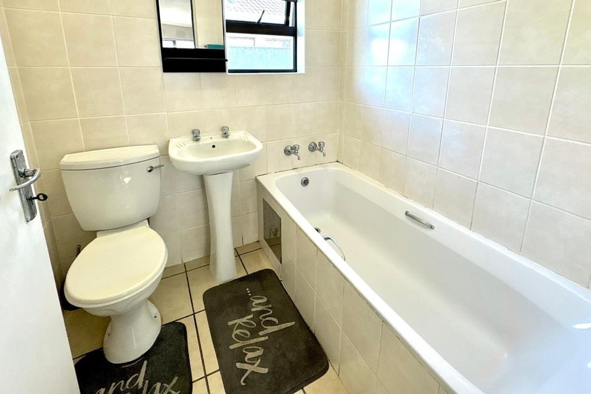 A functional bathroom featuring a pedestal basin, standard toilet, and a bathtub with tiled wall finishes.