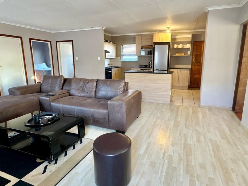 Open-plan living area featuring a functional kitchen with built-in cabinetry, an island, and laminate flooring throughout the combined space.
