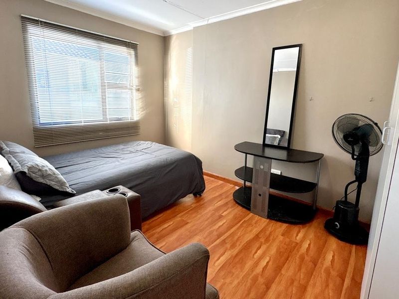 A functional bedroom featuring laminate flooring, neutral wall tones, and a built-in wardrobe, offering a comfortable and practical living space.