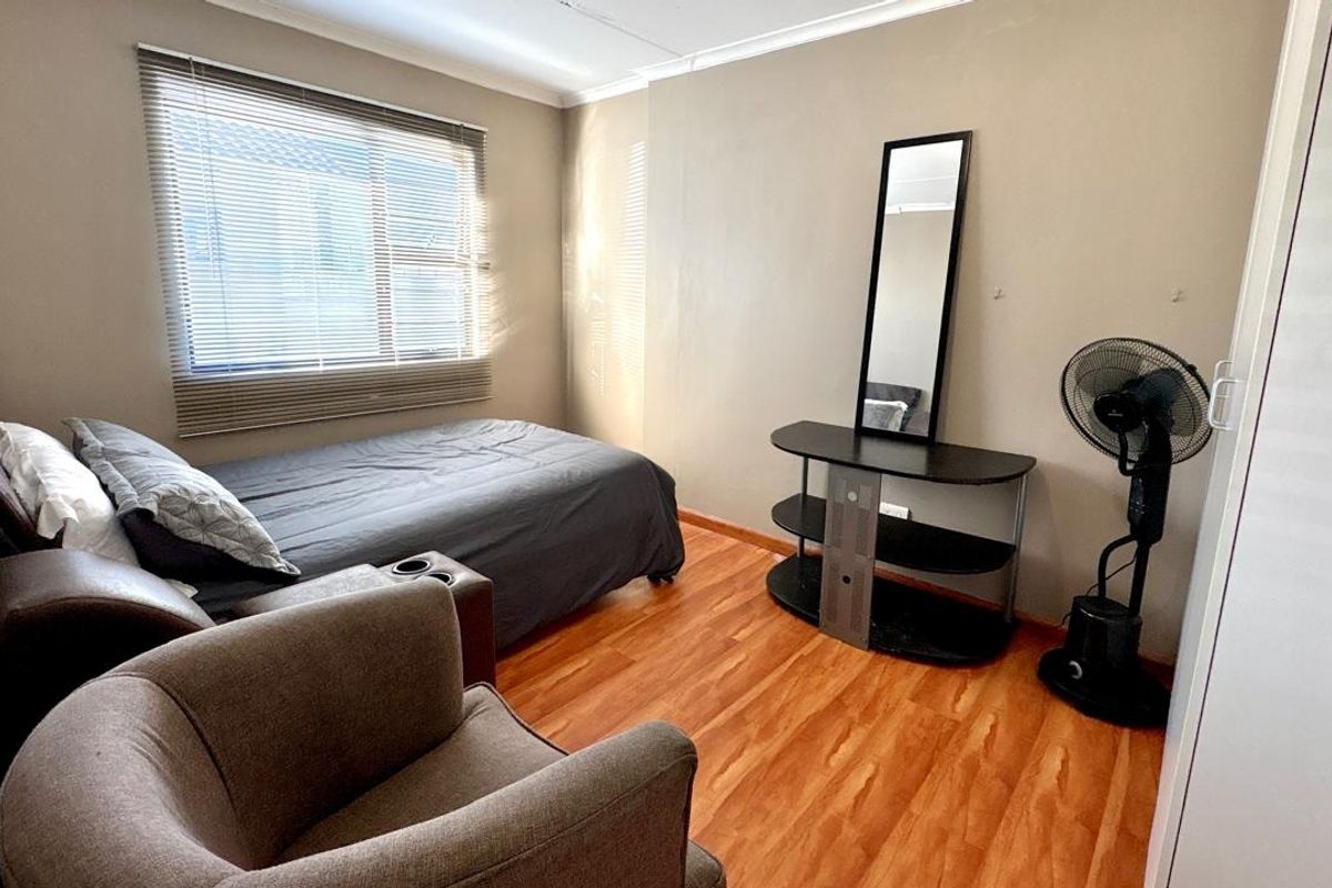 A functional bedroom featuring laminate flooring, neutral wall tones, and a built-in wardrobe, offering a comfortable and practical living space.