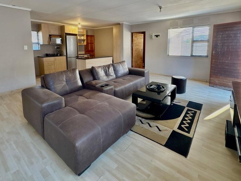 Open-plan living area featuring laminate flooring and an integrated kitchen with built-in cabinetry, providing a functional and connected living space.