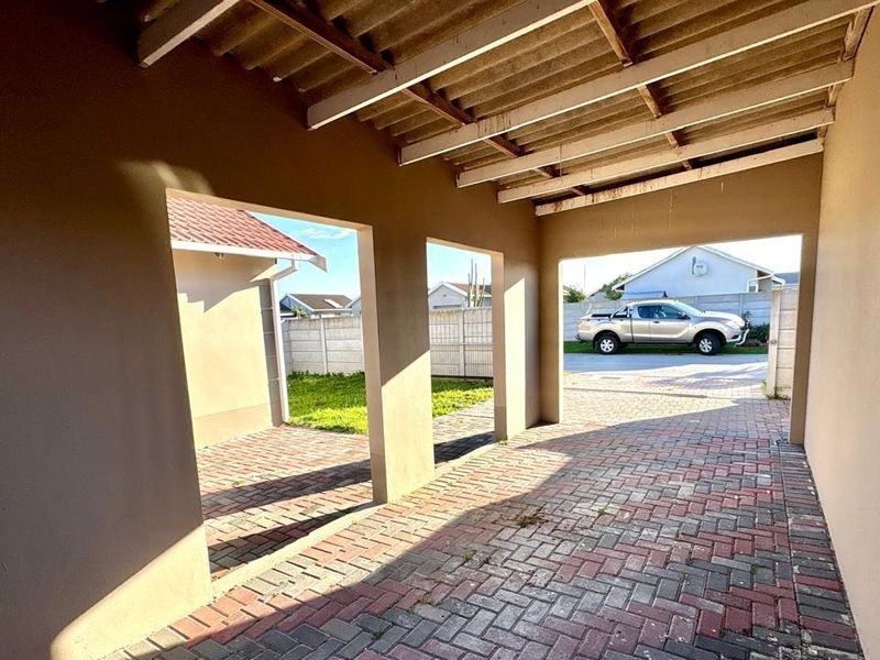 A covered outdoor patio area featuring paved flooring, masonry pillars, and an exposed timber beam ceiling, providing a functional space for outdoor living.