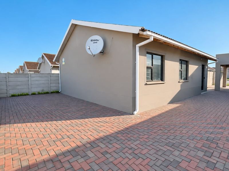 Rear view of the property featuring a paved driveway, precast boundary wall, and a covered carport area.