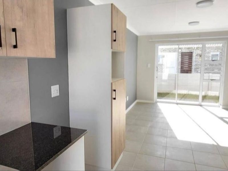 Open-plan living area featuring modern built-in kitchen cabinetry, granite countertops, and large sliding glass doors leading to an outdoor space.