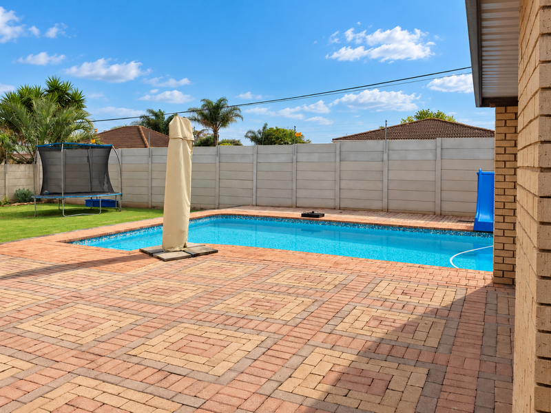 Outdoor pool area featuring a paved patio, swimming pool, and secure perimeter walling, ideal for recreation and entertaining.