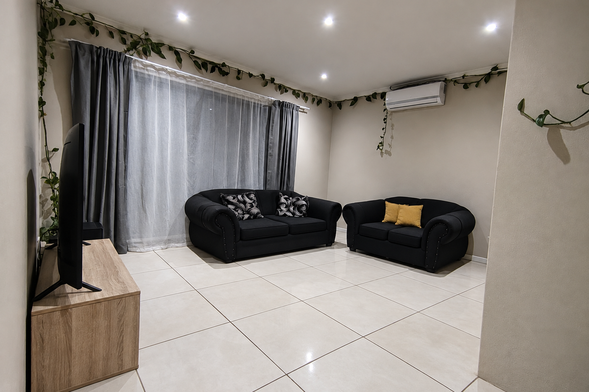 A bright and spacious living room featuring neutral tiled flooring, recessed downlighting, and a wall-mounted split-system air conditioning unit.