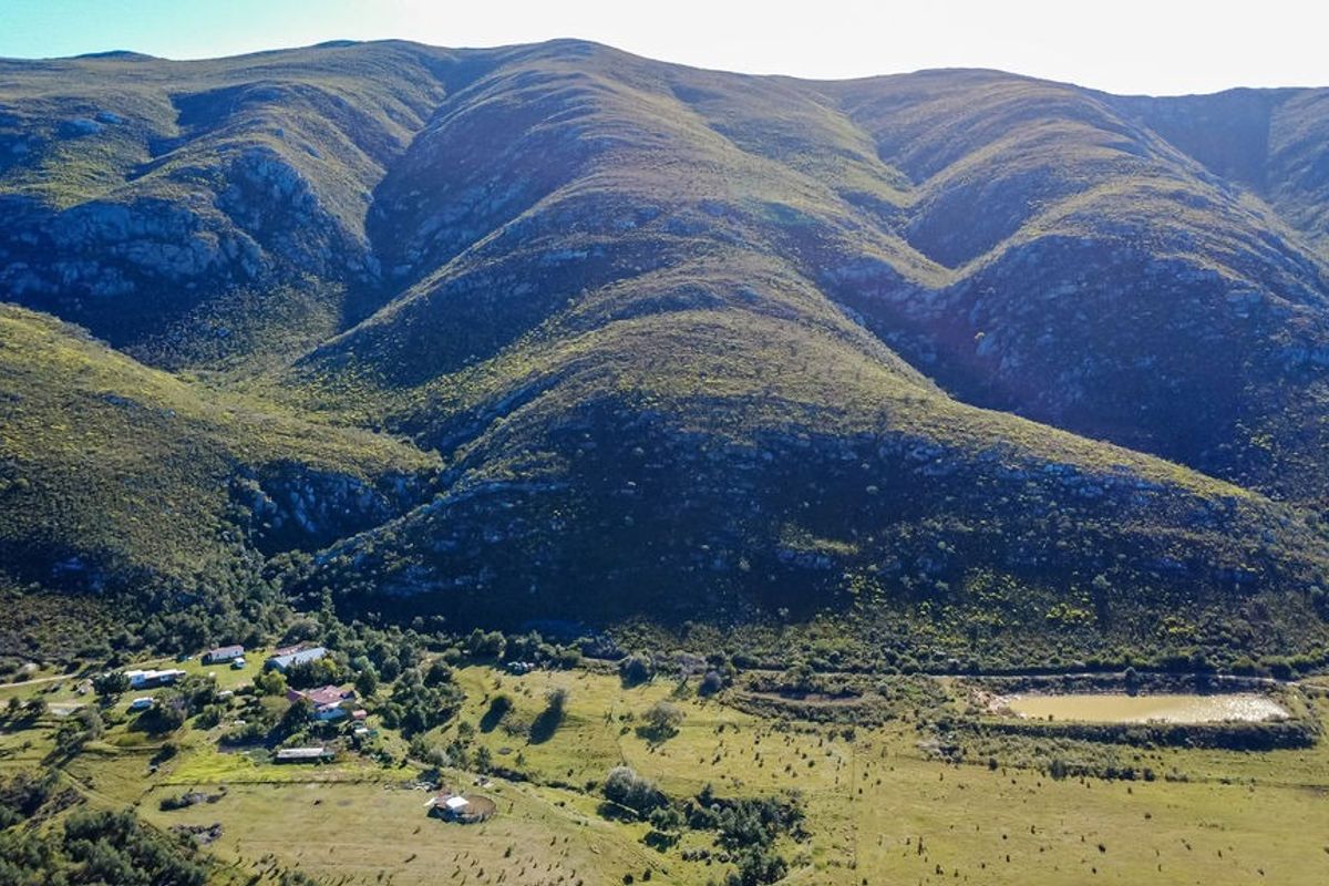 Aerial view of a farm property featuring expansive mountain vistas, open grazing land, and a private farm dam.