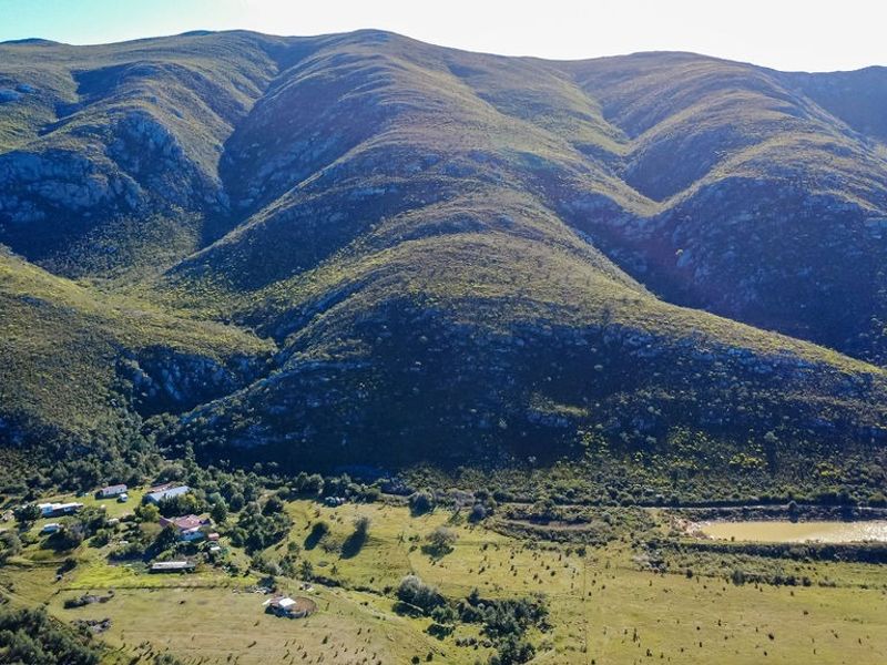 Aerial view of a farm property featuring expansive mountain vistas, open grazing land, and a private farm dam.